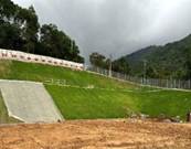 A grassy hill with a fence and a hill with trees in the background

AI-generated content may be incorrect.